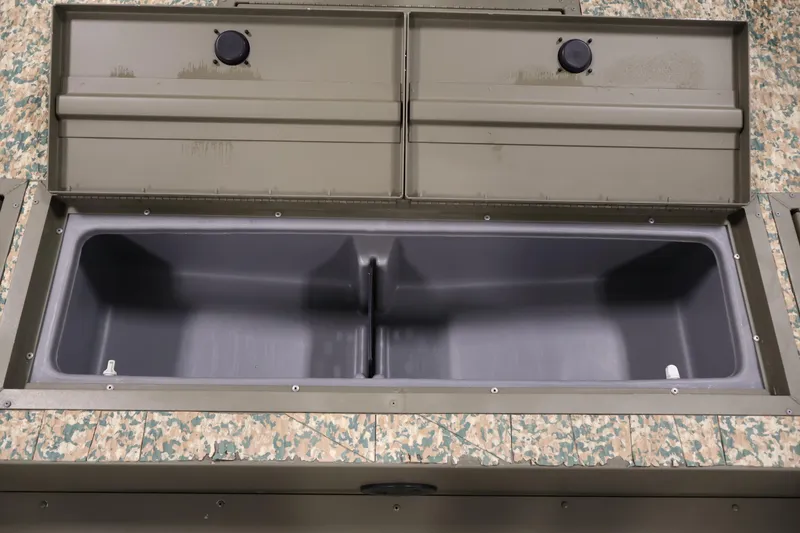 Slide: The Image of Open storage compartment in 2022 Tracker Grizzly 2072 MVX CC boat, featuring camouflage design. - 16