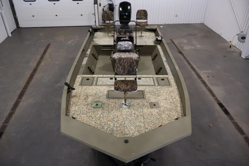 Slide: The Image of 2022 Tracker Grizzly 2072 MVX CC boat in a garage, featuring camo seats and spacious deck. - 9