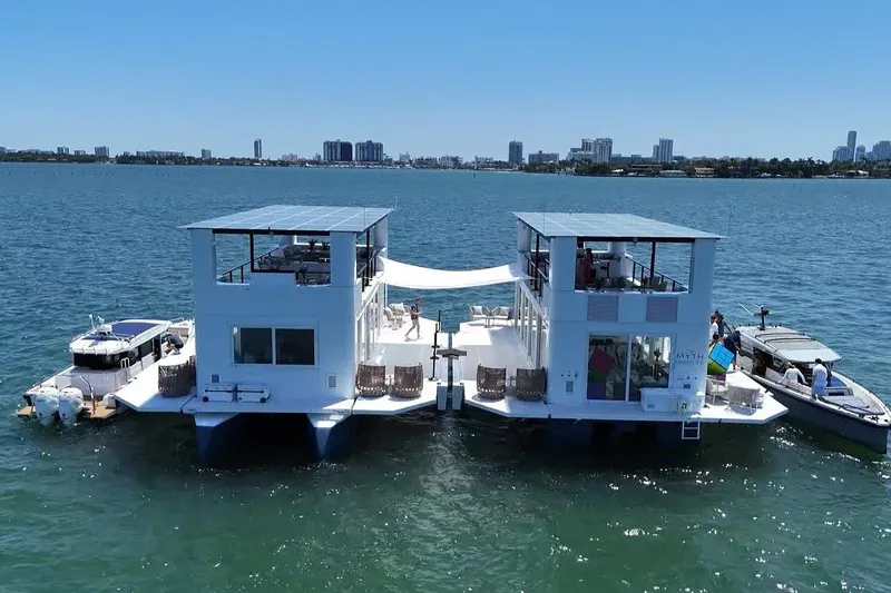 Slide: The Image of Floating ARKHAUS Villa 50, 2025 model, on water with city skyline in background. - 3