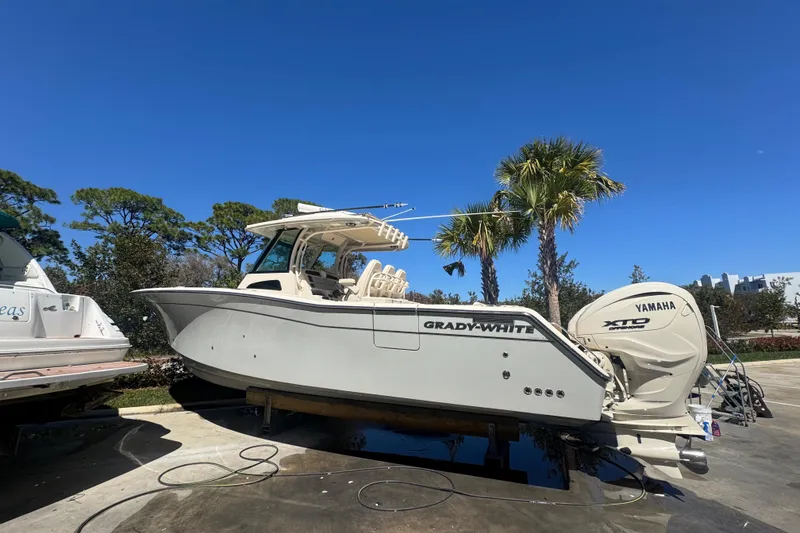 Slide: The Image of 2024 Grady-White Canyon 336 boat with Yamaha engines, parked outdoors under clear blue sky. - 11