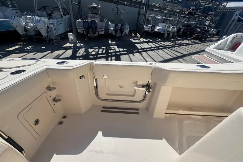 Slide: The Image of 2024 Grady-White Canyon 336 boat interior, showcasing seating and storage features in a marina setting. - 25