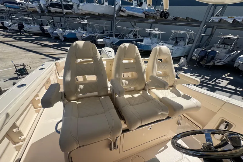 Slide: The Image of 2024 Grady-White Canyon 336 boat with luxurious seating and steering wheel in a marina. - 40