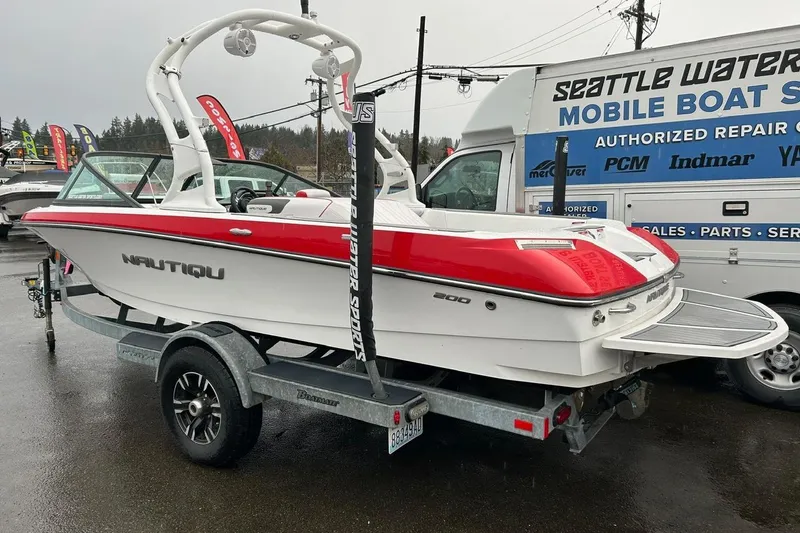 Slide: The Image of 2017 Nautique Ski Nautique 200 Open Bow boat on trailer, parked near service van. - 1