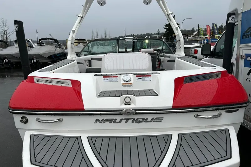 Slide: The Image of 2017 Nautique Ski Nautique 200 Open Bow boat, red and white, rear view in a marina. - 19