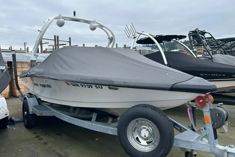 Slide: The Image of 2017 Nautique Ski Nautique 200 Open Bow boat on trailer, covered and parked outdoors. - 3