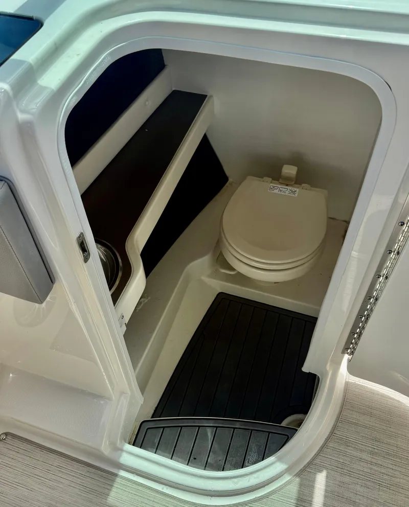 Slide: The Image of 2020 Sea Ray SLX 280 boat interior with compact marine toilet and storage shelves. - 21