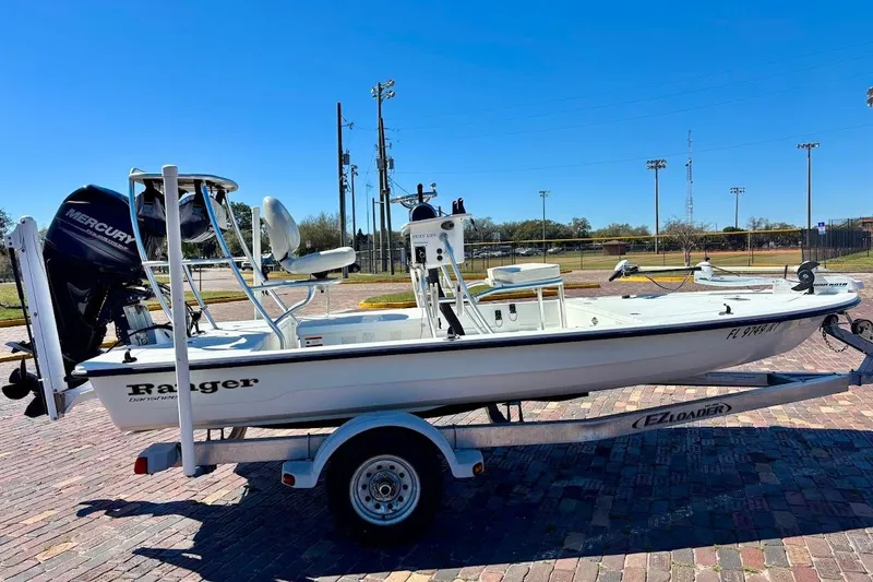 Slide: The Image of 2009 Ranger Banshee boat on trailer with Mercury outboard motor, parked on brick pavement. - 27