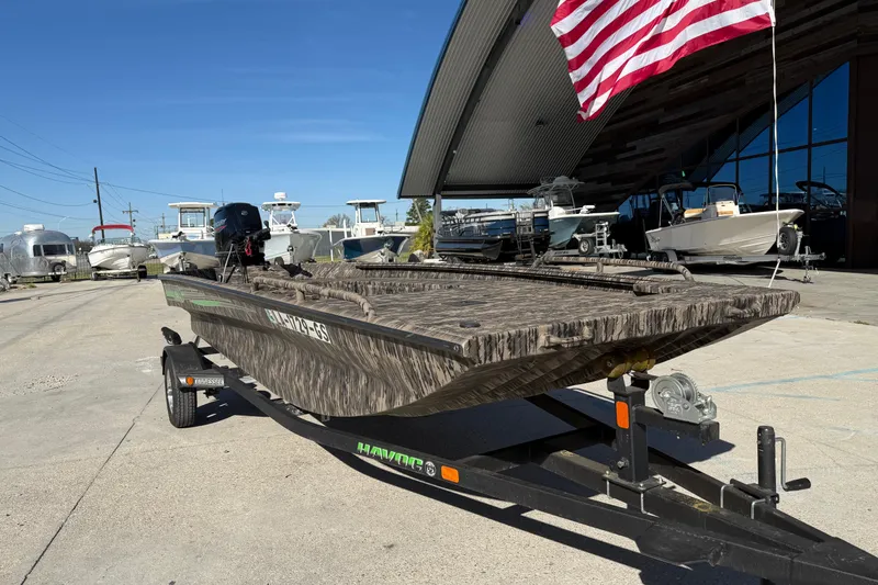 Slide: The Image of 2024 Havoc River Rat 1756 boat on trailer, displayed outdoors with American flag. - 3