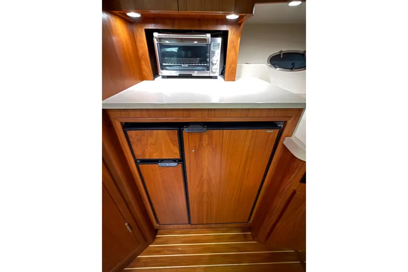 Slide: The Image of 1998 Tiara Yachts 3500 Open galley with wood cabinetry, mini fridge, and countertop oven. - 35