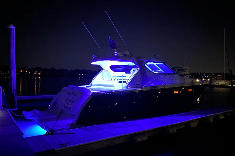 Slide: The Image of 2006 Tiara Yachts 4300 Sovran illuminated with blue lights at night on a dock. - 8