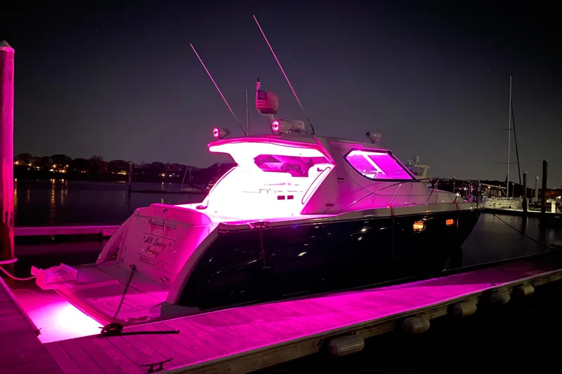 Slide: The Image of 2006 Tiara Yachts 4300 Sovran illuminated with pink lights at night on a dock. - 9