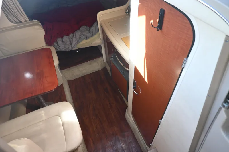 Slide: The Image of Interior of 2005 Sea Ray Sundancer 280, featuring cozy seating and wooden cabinetry. - 16