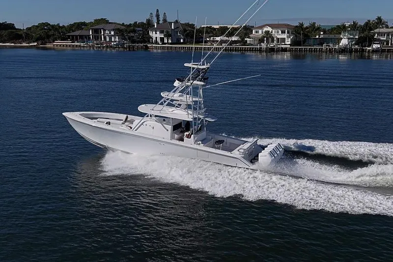 Slide: The Image of A 2025 Sparks 46 boat cruising on a calm waterway near waterfront homes. - 24