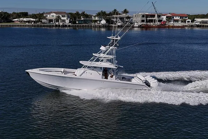 Slide: The Image of 2025 Sparks 46 boat cruising on a calm waterfront with houses in the background. - 25