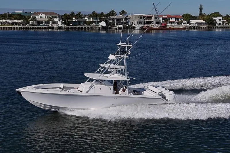 Slide: The Image of A sleek 2025 Sparks 46 boat cruising on a calm waterfront with luxury homes. - 26