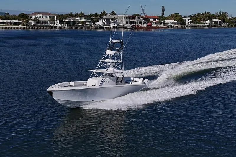 Slide: The Image of A 2025 Sparks 46 boat cruising on a calm waterfront with houses in the background. - 27