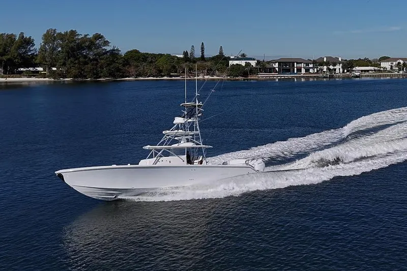 Slide: The Image of A 2025 Sparks 46 boat cruising on a serene waterway near a coastal town. - 31