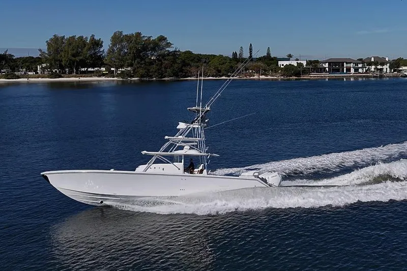 Slide: The Image of 2025 Sparks 46 boat cruising on a serene lake with a scenic shoreline. - 32