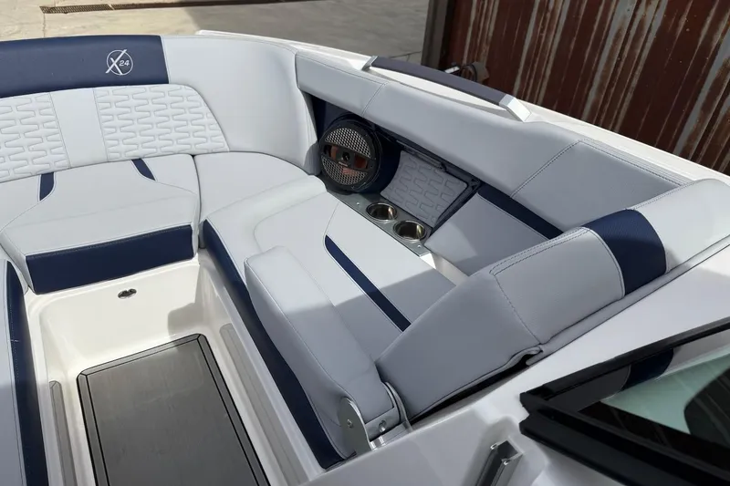 Slide: The Image of 2024 MasterCraft X24 boat interior with white and blue seating, cup holders, and speaker. - 12