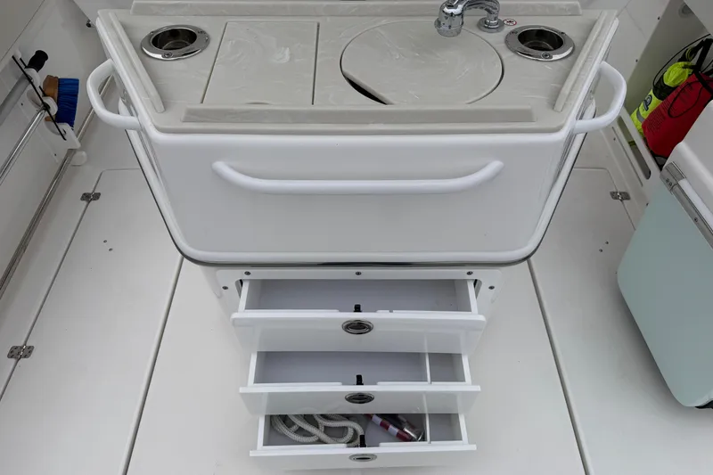 Slide: The Image of 2024 Edgewater 262CC boat interior with sink, storage drawers, and safety equipment. - 19