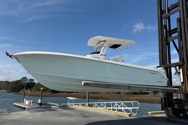 Slide: The Image of 2024 Edgewater 262CC boat lifted at dockside under clear blue sky. - 2