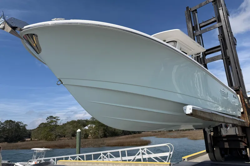Slide: The Image of 2024 Edgewater 262CC boat on lift, showcasing sleek hull design against blue sky. - 4