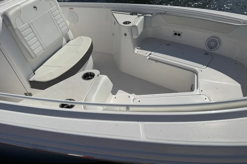 Slide: The Image of 2024 Edgewater 262CC boat interior with seating and cup holders, on calm water. - 6