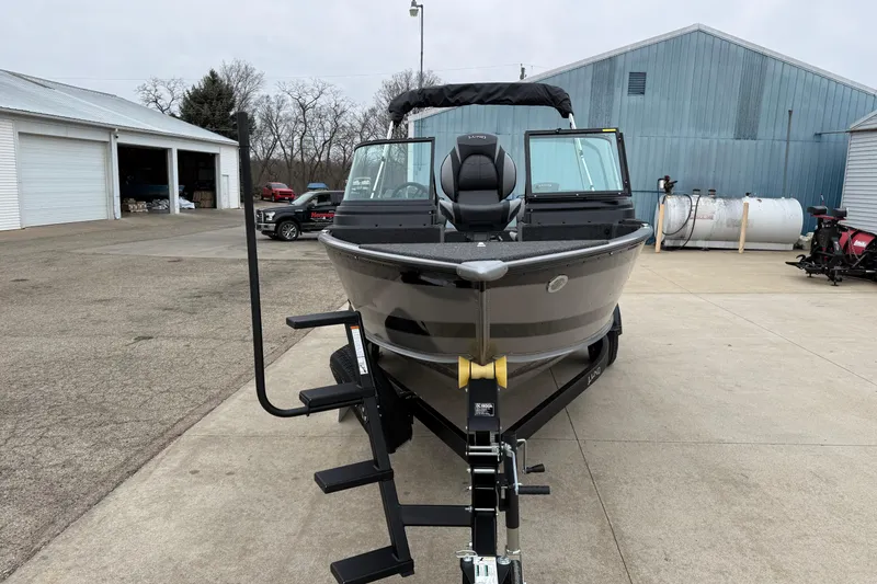 Slide: The Image of 2026 Lund 1875 Impact XS Sport boat on trailer in industrial setting. - 2