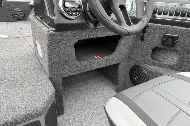 Slide: The Image of Interior of 2026 Lund 1875 Impact XS Sport boat, featuring steering wheel and dashboard controls. - 26