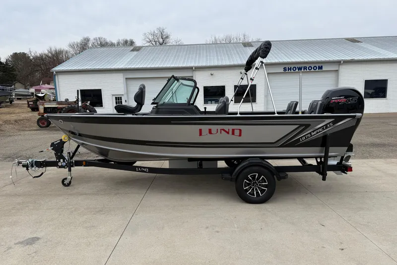 Slide: The Image of 2026 Lund 1875 Impact XS Sport boat on trailer outside showroom. - 4