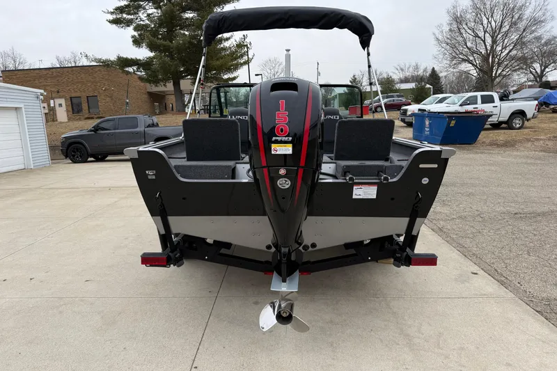 Slide: The Image of 2026 Lund 1875 Impact XS Sport boat with 150 HP motor, parked outdoors. - 6