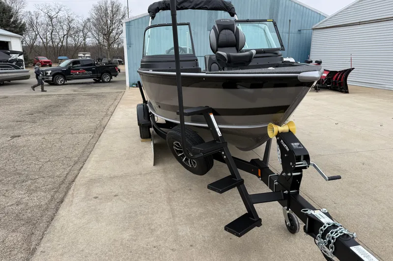 Slide: The Image of 2026 Lund 1875 Impact XS Sport boat on trailer, parked outdoors near buildings. - 9