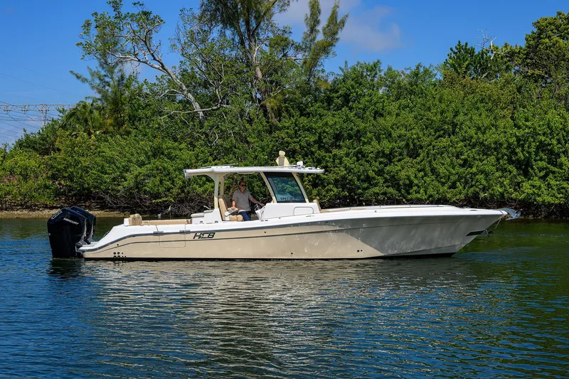 Slide: The Image of 2024 HCB 39 Speciale boat cruising on a calm river with lush greenery. - 52