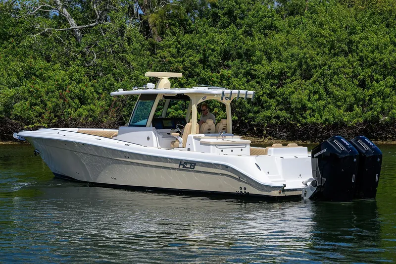 Slide: The Image of 2024 HCB 39 Speciale boat cruising on a calm waterway, surrounded by lush greenery. - 58