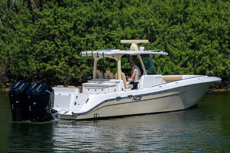 Slide: The Image of 2024 HCB 39 Speciale boat cruising on water near lush greenery. - 60