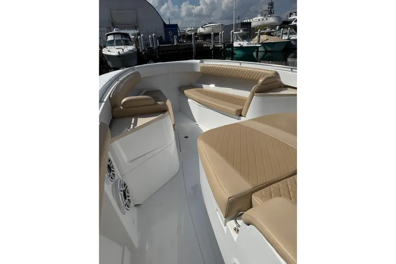 Slide: The Image of 2024 HCB 39 Speciale boat interior with tan seating and speakers at a marina. - 7