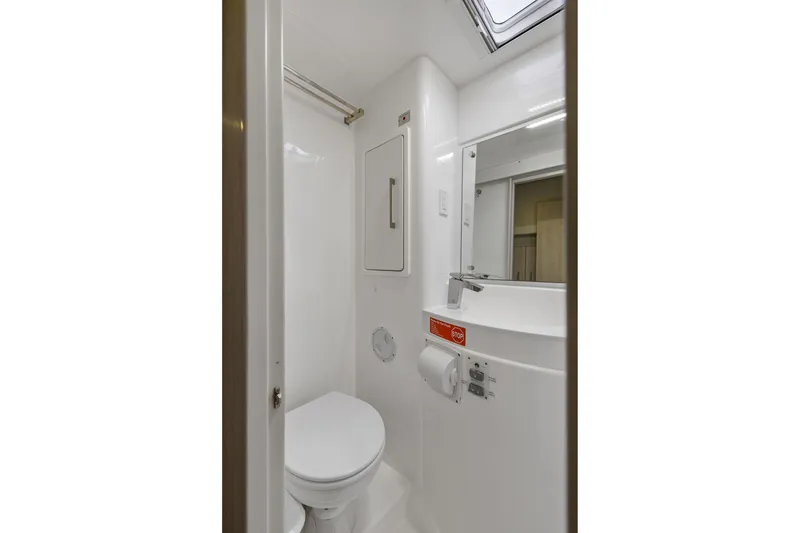 Slide: The Image of Compact bathroom in 2015 Leopard 58 yacht, featuring toilet, mirror, and storage. - 62