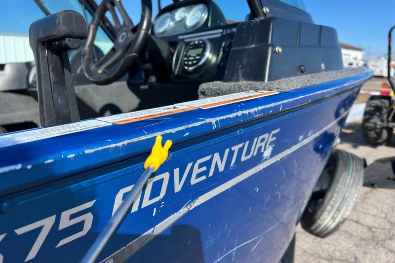 Slide: The Image of 2020 Lund 1675 Adventure Sport boat, blue exterior, close-up view with steering wheel visible. - 43