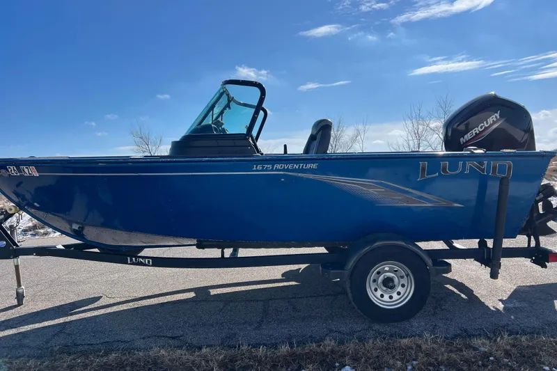 Slide: The Image of 2020 Lund 1675 Adventure Sport boat on trailer, blue exterior, clear sky background. - 9