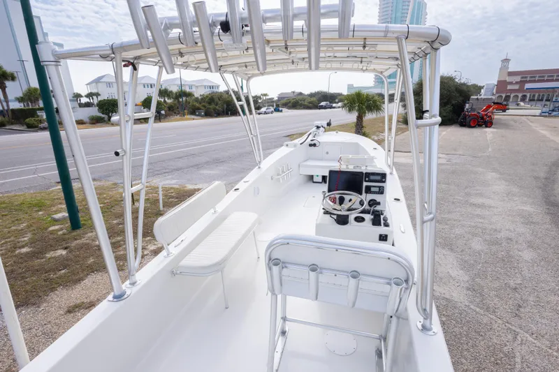 Slide: The Image of 2017 Andros Tarpon 26 boat with T-top, console, and seating, parked near a road. - 26