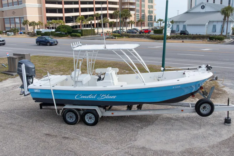 Slide: The Image of 2017 Andros Tarpon 26 boat on trailer, labeled "Coastal Blues," parked near a road. - 3