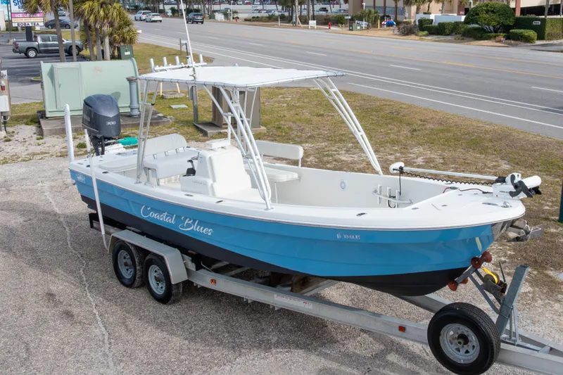 Slide: The Image of 2017 Andros Tarpon 26 boat on trailer, blue hull, parked near road. - 7