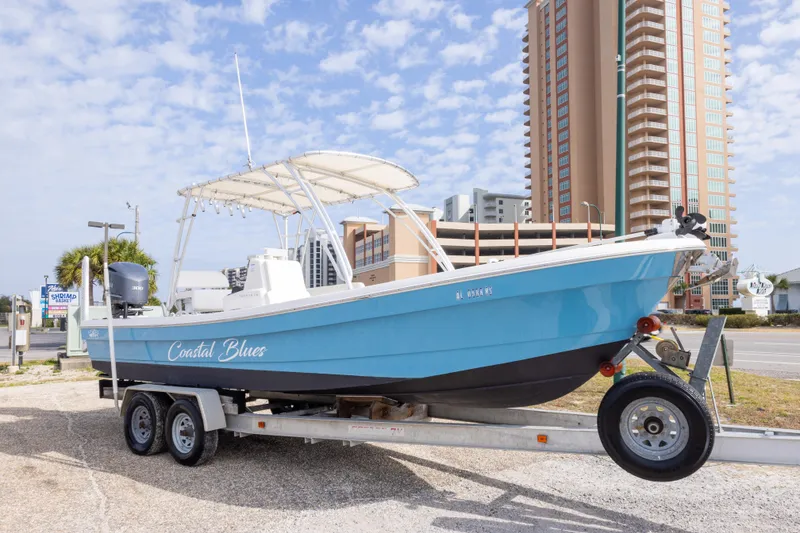 Slide: The Image of 2017 Andros Tarpon 26 boat named "Coastal Blues" on trailer, cityscape background. - 1