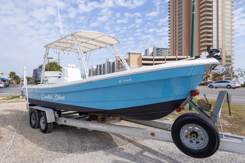 Slide: The Image of 2017 Andros Tarpon 26 boat on trailer, blue hull, urban background. - 30