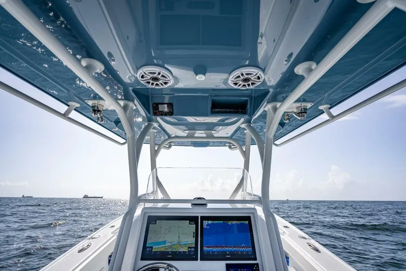 Slide: The Image of 2025 Yellowfin 34 Offshore boat interior with navigation screens, ocean view, and blue canopy. - 16