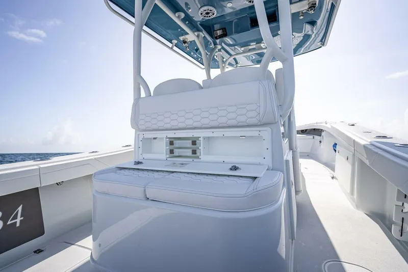 Slide: The Image of 2025 Yellowfin 34 Offshore boat interior with white seating and storage, under clear blue sky. - 20