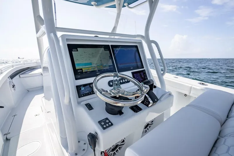 Slide: The Image of 2025 Yellowfin 34 Offshore boat dashboard with dual screens and steering wheel, ocean view. - 8