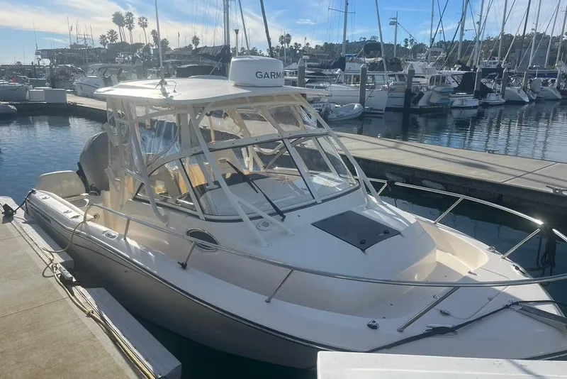 Slide: The Image of 2023 Grady-White Adventure 218 boat docked in a marina with sailboats. - 2