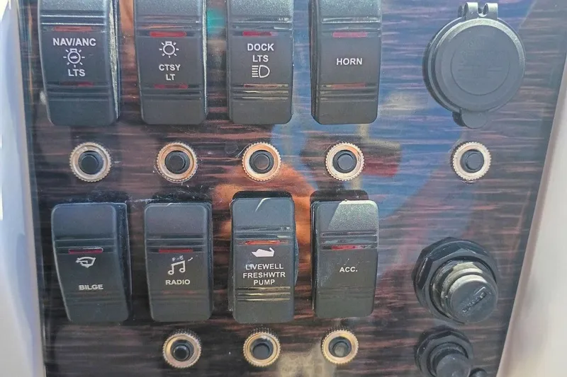 Slide: The Image of Control panel of a 2026 Starcraft SVX 211 OB boat with various switches. - 17