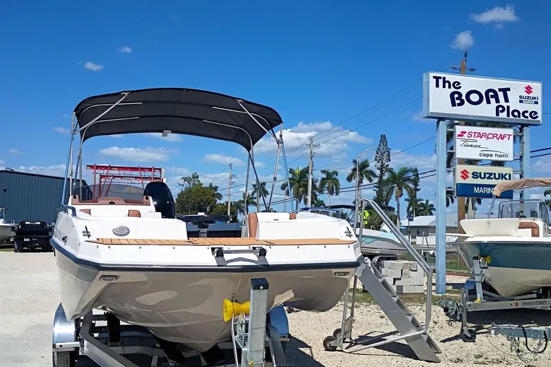 Slide: The Image of 2026 Starcraft SVX 211 OB boat displayed at dealership under clear blue sky. - 2